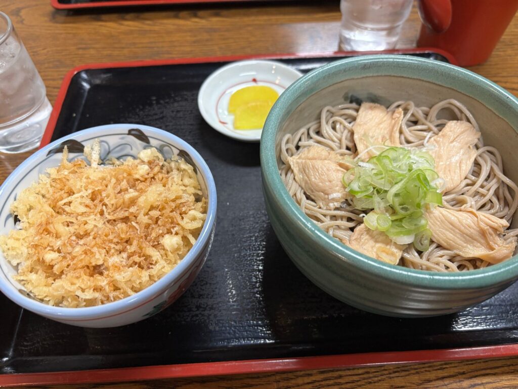 お盆にのった、肉とねぎをのせた新そばと、天かすをたっぷりのせた丼、たくあんの小皿