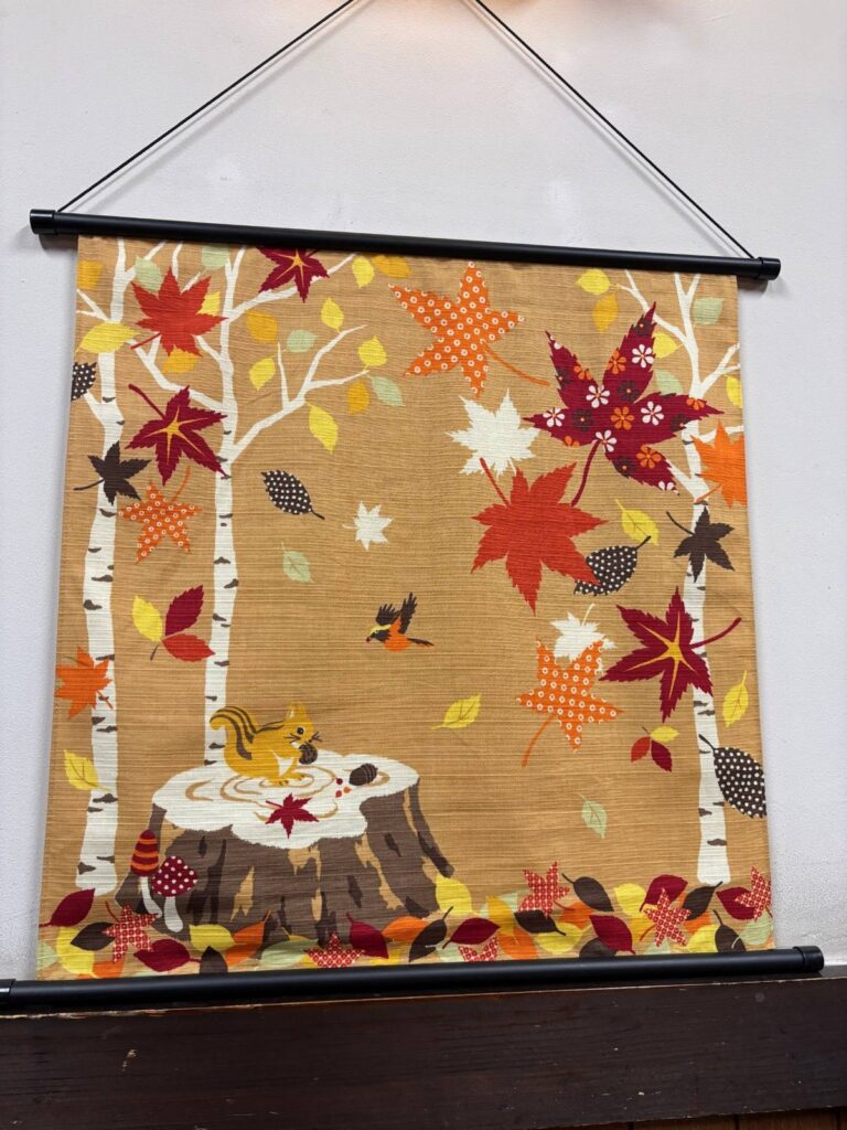 紅葉と白樺の林、切り株の上のリスが描かれた秋のタペストリー